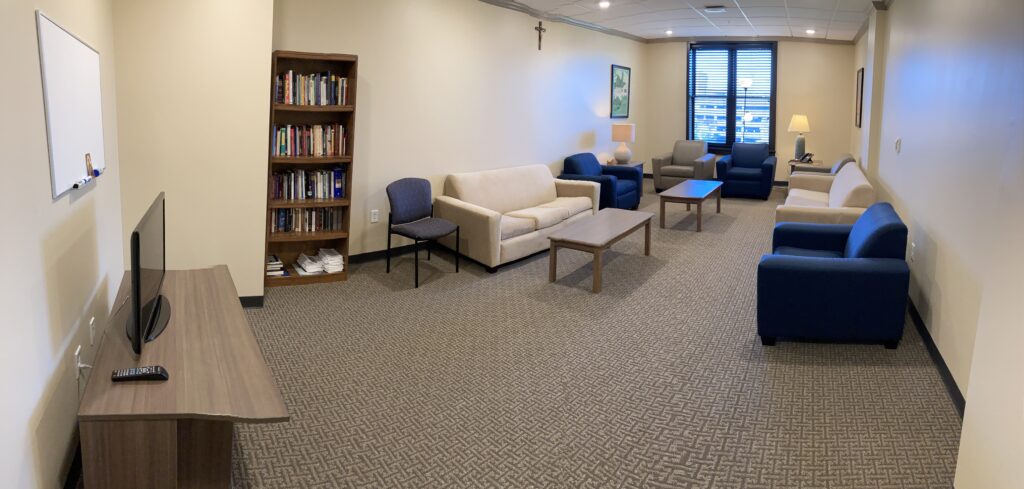 Third Floor Lounge with a couple of couches, comfy chairs, a tv, and bookshelf accommodates up to 16 people for small group discussions or leisure time.