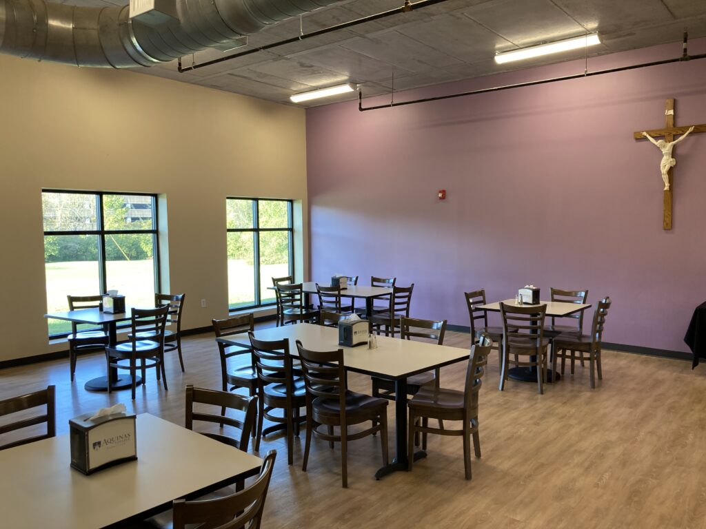 Siena Hall Conference Center Dining Hall with large, picturesque windows and tables and chairs to accommodate 50 people.