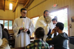 Pat McMahon, '21, left, assists Fr. Menezes during a Eucharistic Procession. Photo courtesy of UCAT.